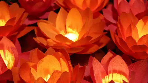 National Trust red paper flowers grouped together, with small tea lights in the center of each flower