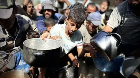 getty images palestinian children wait in line to receive the food distributed by charitable organizations in khan yunis