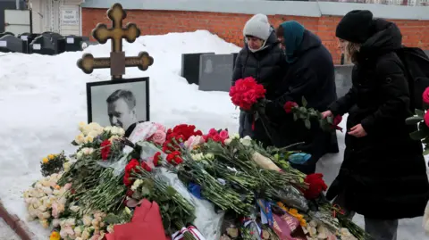 EPA Women lay flowers on a grave