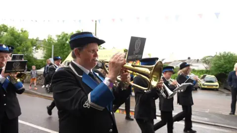 A brass instrument being played by a person wearing a black and blue uniform