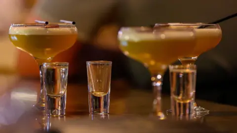 Three cocktails and three shots with a blurred background.