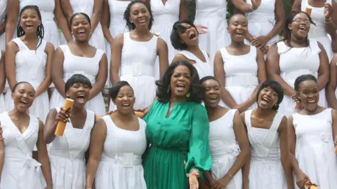 Oprah Winfrey stands with girls from her school at their graduation.