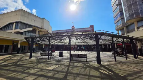 Paul Moseley/BBC The central plaza of Anglia Square. There is a spiderweb style canopy over the centre - with 60s brutalist architecture surrounding it.