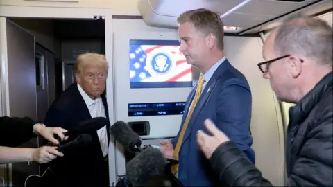 Donald Trump talks to reporters on Air Force One.