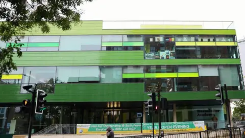 Getty Images The outside of Westminster Academy, a modern green building with large windows 