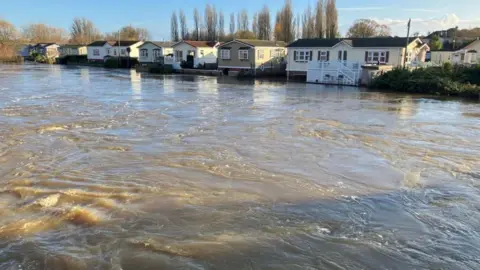 A row of park homes with the flood river coming up to the steps