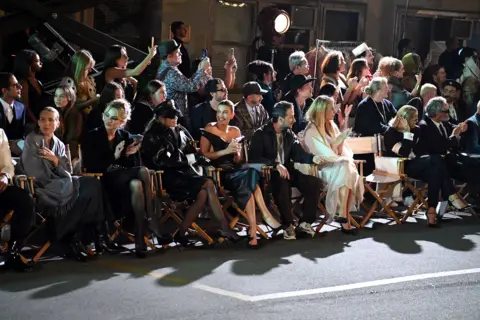 Getty Images Gwyneth Paltrow and Miley Cyrus sitting on the front row at the Vogue World Catwalk show along with other audience members enjoying the catwalk show