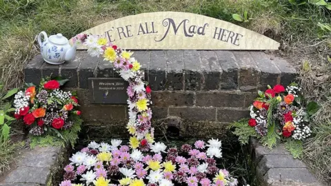 Malvern Hills District Council A teapot is placed above a well and pink, yellow and white flowers are arranged to look like tea pouring out of the spout.