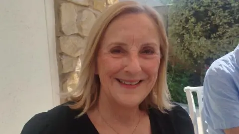 Paul Burnell/BBC Julie Swire has blonde hair and a black dress.
