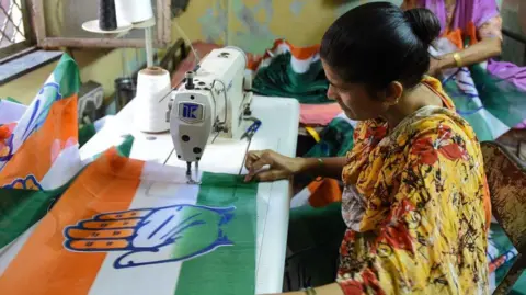 An Indian woman stitches a flag of the Congress party at her residence, ahead of India's general election, in Ahmedabad on April 1, 2019