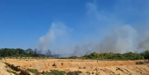 Heathland fire in Blackwater, Camberley - smoke is seen coming from shrubs and trees 