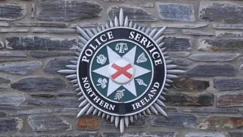 A PSNI badge on a stone wall.