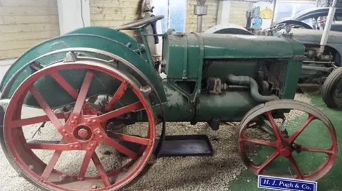 An old green tractor with red metal wheels.