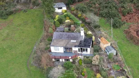 BBC Aerial view of Daniel San Diego's house, a white villa with a balcony offering striking views of rolling hills and a well-manicured garden