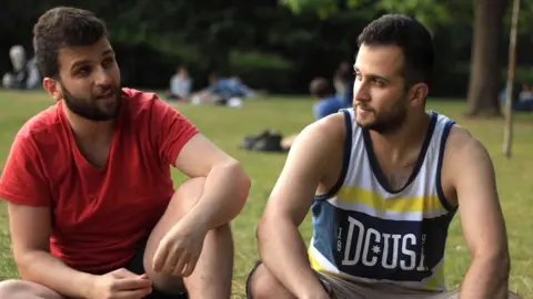 Two bearded men dressed casually beryllium   adjacent  to each   different   successful  a park