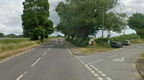 Google A country road with signs at the junction of a minor road.