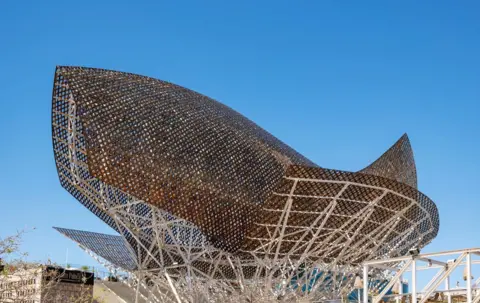 Petr Svarc/UCG/Universal Images Group via Getty Images Peix d'Or, Goldfish sculpture designed by Frank Gehry, in Barcelona is seen against a bright blue sky
