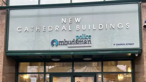 A sign about the door of the Police Ombudsman for Northern Ireland office in Belfast.   The sign says "New Cathedral Buildings" and the address - 11 Church Street. 