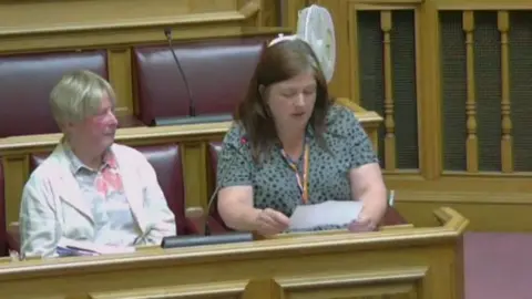 Dorset Council Becky Brookman (right) at the May's council meeting. Another person is sitting next to her. Ms Brookman is reading from a sheet of paper.
