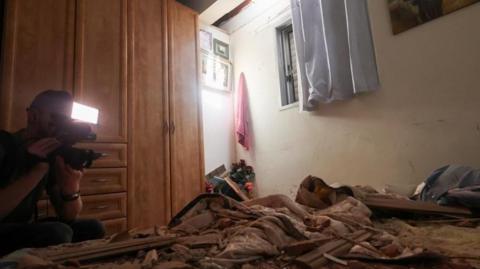 A media person works in a room that was damaged after rockets were fired  in Herzliya, Israel, 26 May 2024