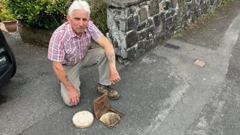 Dave Winter kneeing over his water meter