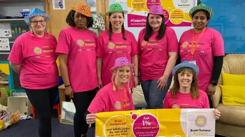 Handout Kirsty Connell and school staff with a Brain Tumour Research sign