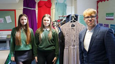 Betsan, Erin and Kieran stood in front of donated prom dresses.