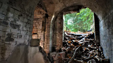 Interior shot of ice house at Deepdene Estate in Dorking showing piles of rubble by the entrance