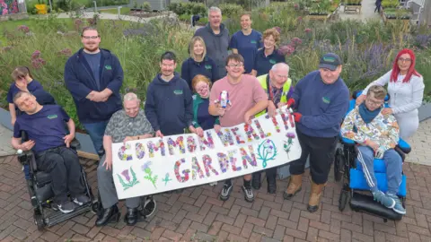 Gordon Terris Workers and people who use Parklea;s facilities standing in front of the Saltire garden, on display in a new location