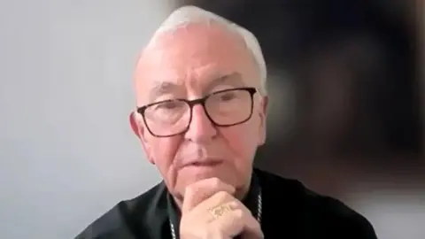 BBC/CBCEW Screengrab of an exclusive interview given by Cardinal Vincent Nichols - who has short white hair and large dark brown glasses - to the BBC. He is resting his chin on one of his hands. 