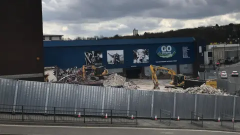 Local Democracy Reporting Service Demolition of a former retail site. There is rubble and two diggers.