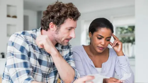 Getty image a man and woman see their bills on a kitchen table