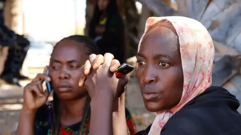 EPA Two women, who are parents of kidnapped schoolchildren wait outside St Mary's Private Catholic School in Papiri