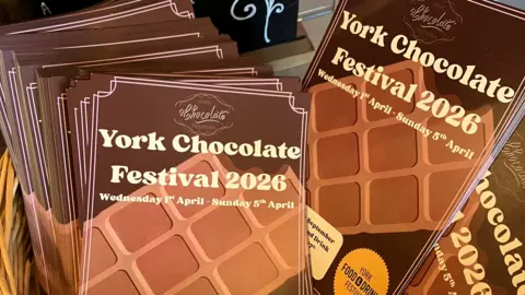 Leaflets for the York Chocolate Festival 2026 in a basket. They are brown and have the image of a tablet of chocolate on them.