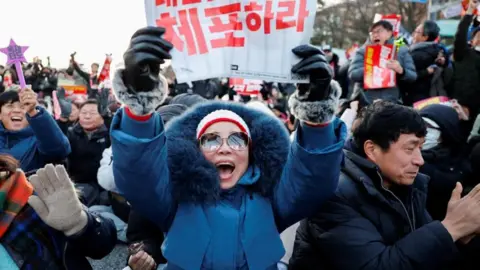 Reuters People in South Korea celebrate after parliament passes a motion to impeach President Yoon Suk Yeol