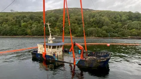 Landing craft Julie Anne being lifted by straps using a crane from the site of its sinking