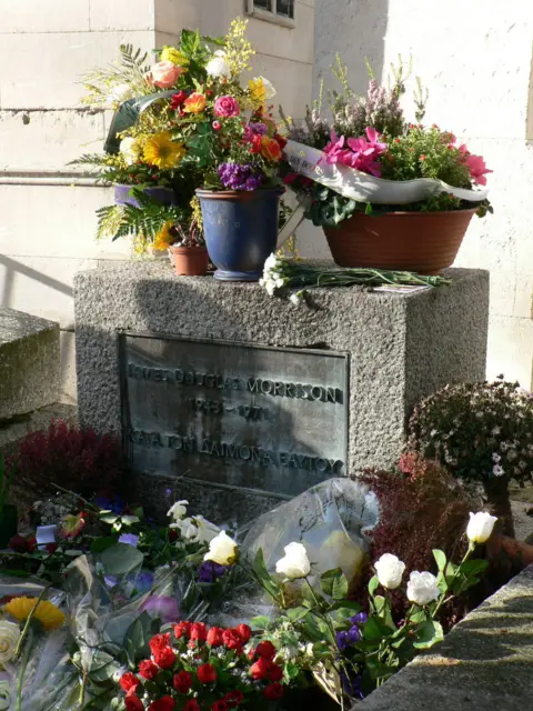 Flowers cover the grave of Jim Morrison