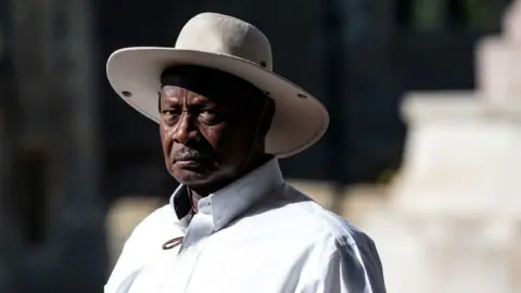 Getty Images Ugandan President Yoweri Museveni wears a white shirt and a wide hat that matches. 