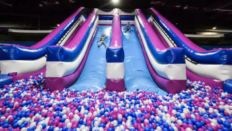 Fun Parx A large inflatable slide with two children sliding down it can be seen, with a ball pit at the bottom.