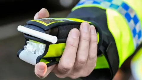 Getty Images The hand of a police officer holding out a roadside breath test device