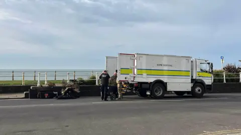 George Carden/BBC A bomb disposal van parked at the side of the road. The back doors are open and people are retrieving equipment from it.