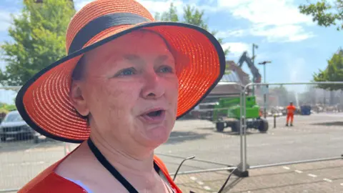A close up of Nicola standing in front of metal fencing infront of the demolitions site 