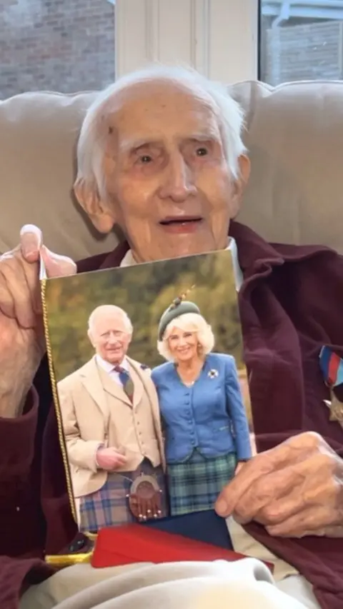 Tony Winterburn holding a birthday card with a picture of the King and Camilla