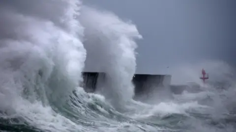 AFP via Getty Images Large waves in western France spraying whitewash up high as it collides with a port 