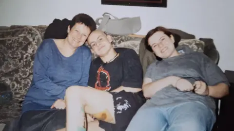 Family photograph David Wragg (left) sitting on a sofa with his mother Sharon and sister Hermione when he was having cancer treatment 