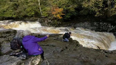 Photographers gather to take photos of salmon at the stream