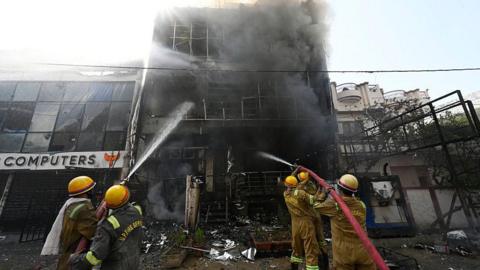 Firefighters douse the flame in a building that killed 15 in Lucknow