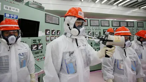 Getty Images A worker measures radiation levels at the Fukushima Daiichi nuclear power station in 2014.