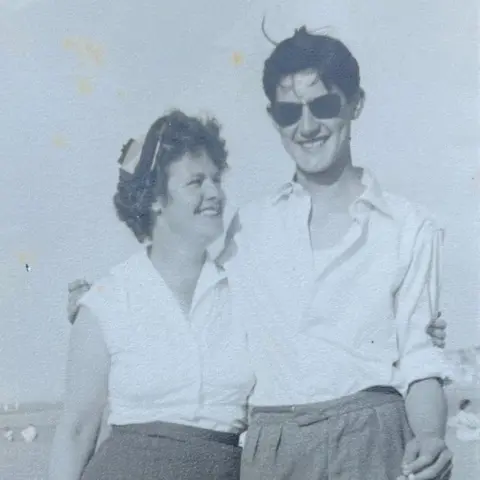 David Balfour David Balfour with his mother Doris in 1957. Both are smiling and wearing white shirts. He is wearing sunglass and has his arm around his mother. The sea can be seen in the background.