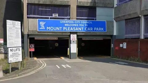 Google A multi-storey car park entrance with a large blue sign with white writing which reads: Liverpool City Council welcomes you to Mount Pleasant Car Park. A white sign with black writing reads: No lifts.